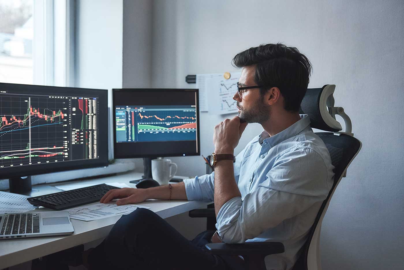 Young male day trader having a successful day watching stock markets online at desk