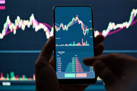 Concept of day trader studying stocks on graph on phone green for buy red for sell