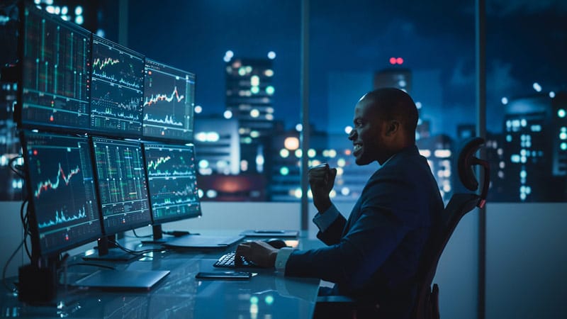 Day trader at night in office celebrating after reading chart patterns and meeting profit targets