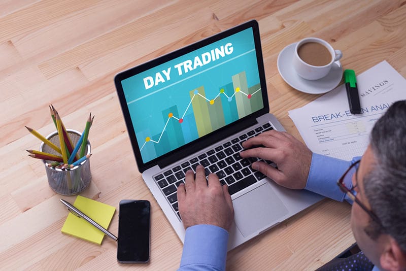 Senior man working at laptop with day trading in white letters
