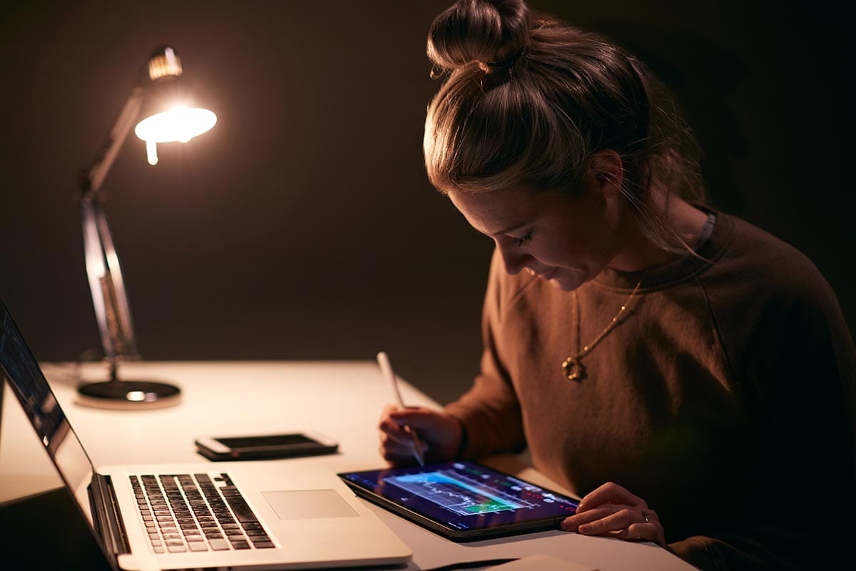 Female novice day trader sitting at desk working on a trading mentorship program