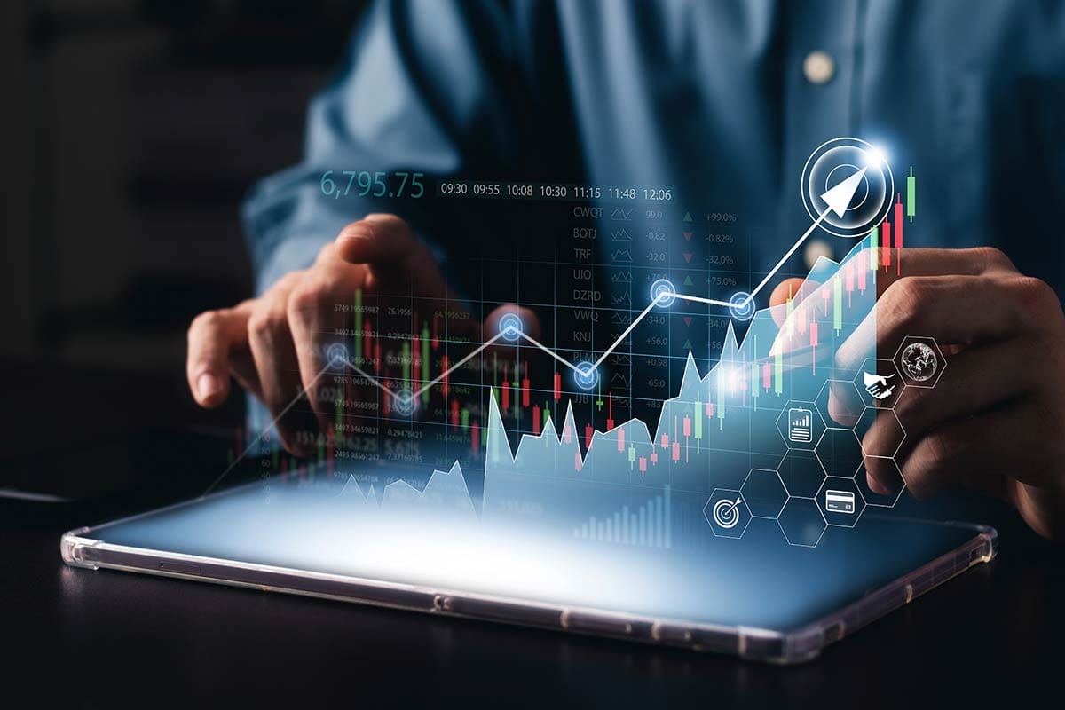 Businessperson typing on tablet with red and green bar charts spiraling upwards