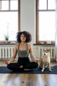 Woman doing yoga with dog to manage emotions in trading