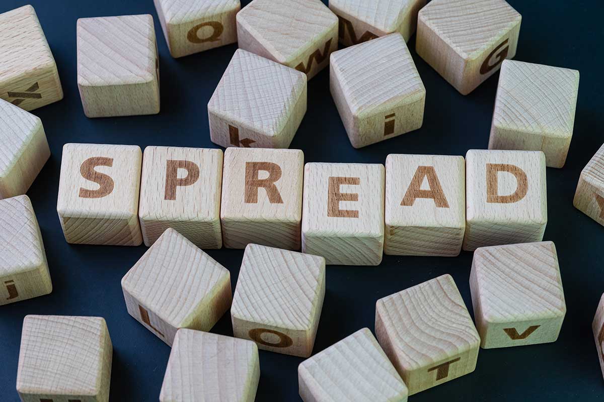 Wooden blocks with letters and numbers burned into them surround 6 blocks roughly lined up that spell, “spread.”