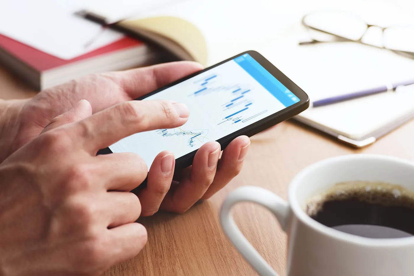 Close up of male hands man looking at Forex charts on smartphone