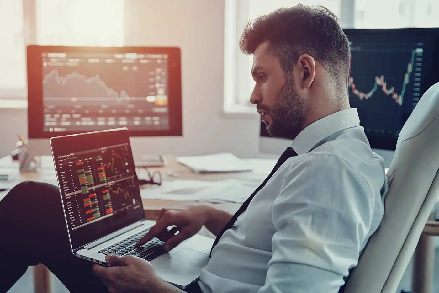 Young successful day trader contemplating position for the day while studying laptop