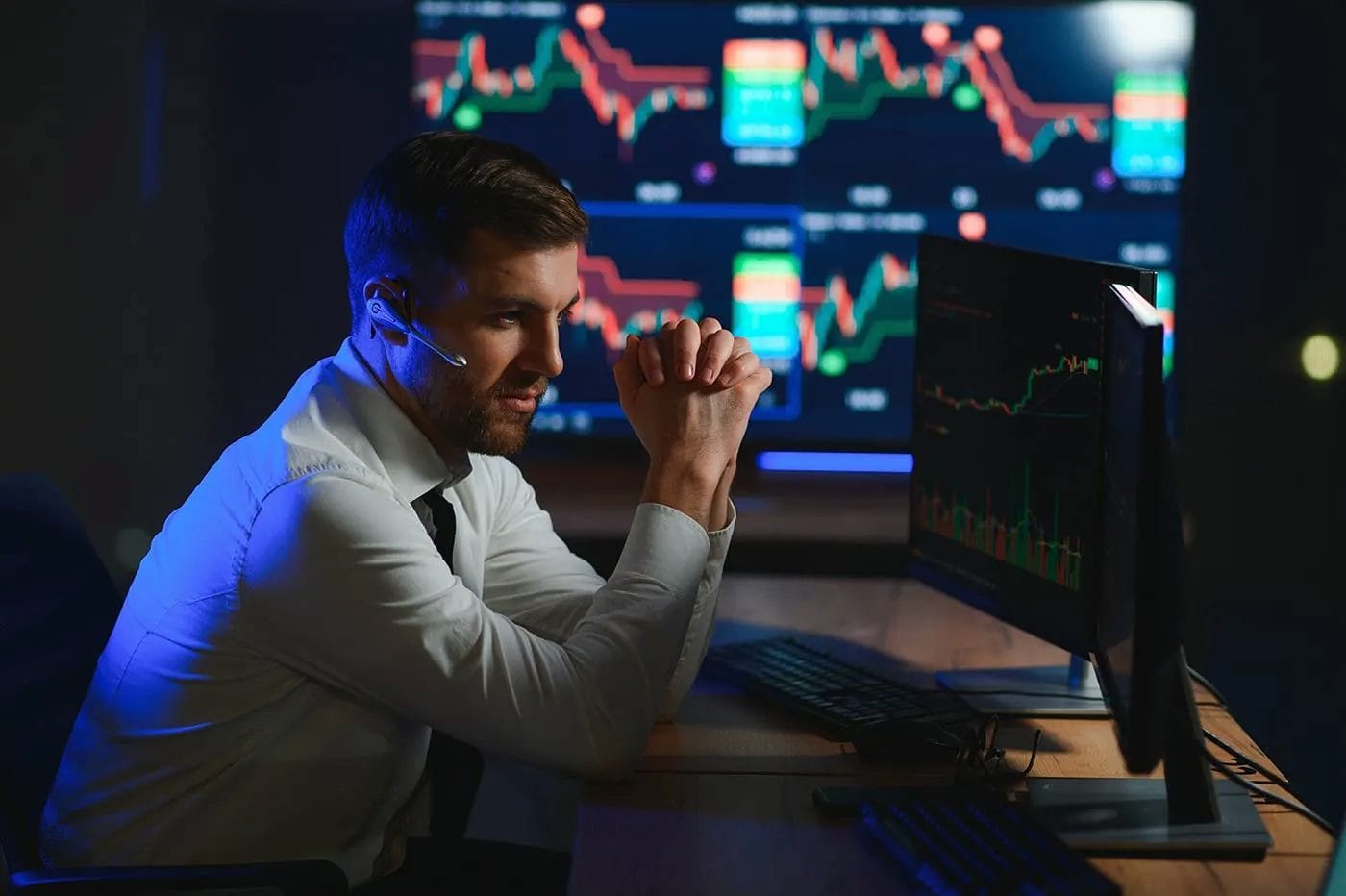 Side view of successful young male day trader studying market trends on screens