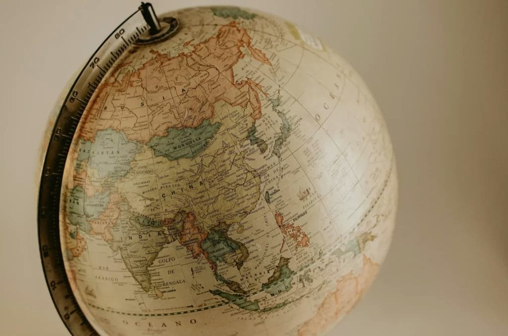 The image shows a vintage globe with a focus on Asia, including countries like Russia, China, India, and Japan.